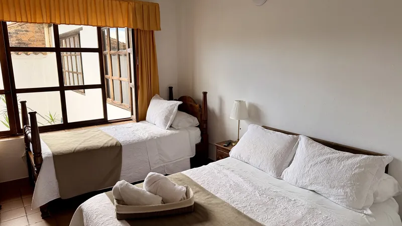 Habitación San Isidro con cama doble, cama sencilla y ventana grande de madera