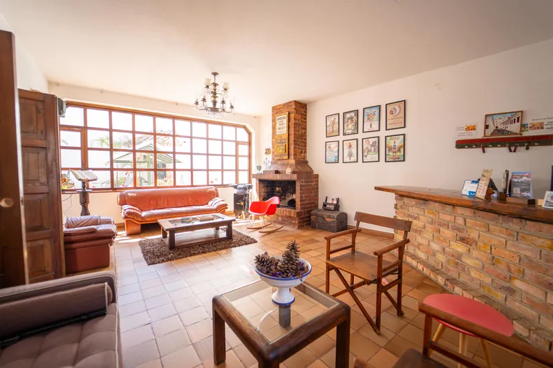 Sala de recepción con chimenea de ladrillo, muebles de cuero y ventanal hacia el patio
